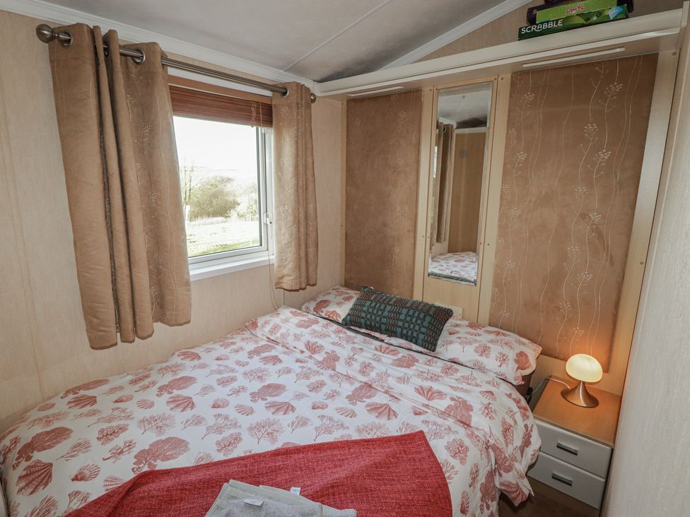 A bedroom with a bed and window at Rhosgranog Caravan Llandeloy near Solva