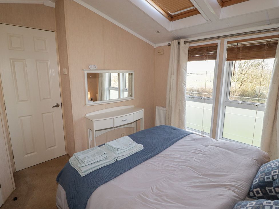 A bedroom with a bed and a mirror at Rhosgranog Caravan in Llandeloy near Solva