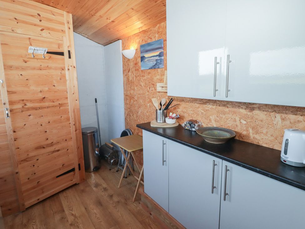 A kitchen with cabinets and a table at Rhosgranog Shepherds Hut in Llandeloy near Solva