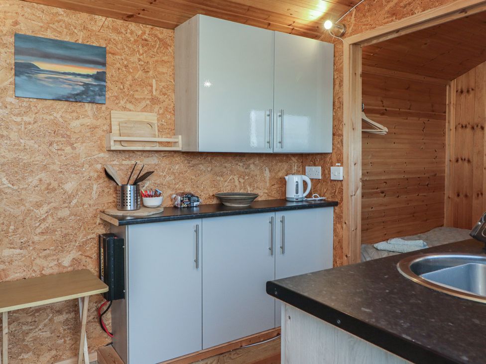 A kitchen area with cupboards and sink at Rhosgranog Shepherds Hut Llandeloy near Solva