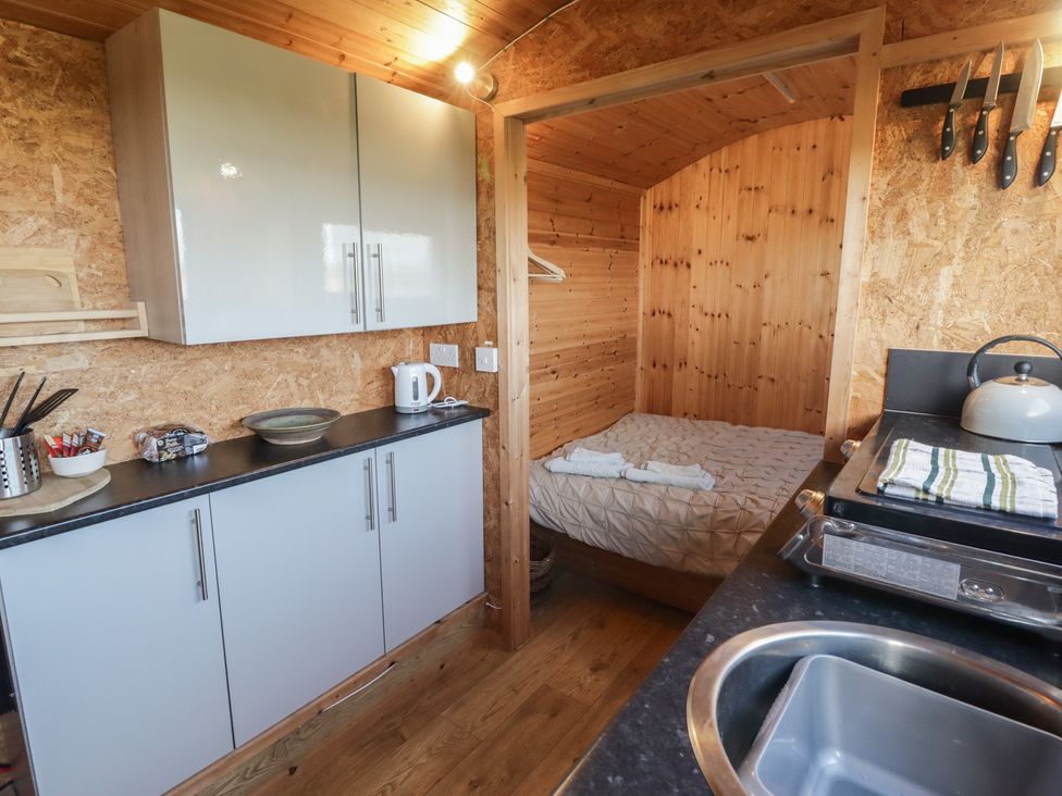 A kitchen with a bed and cabinetry at Rhosgranog Shepherds Hut Llandeloy near Solva