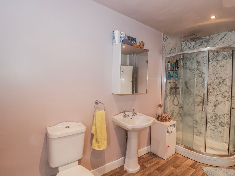 A bathroom with a sink, toilet, mirror, and shower at The Flat House in Taunton