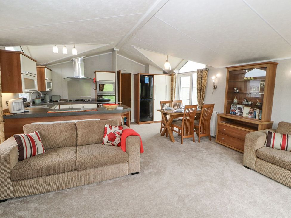 A living room with a sofa, dining table and kitchen at No 8 Hillcote Lodge in Cockermouth
