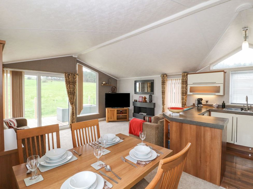 A living room with a dining area and kitchen island at No 8 Hillcote Lodge in Cockermouth