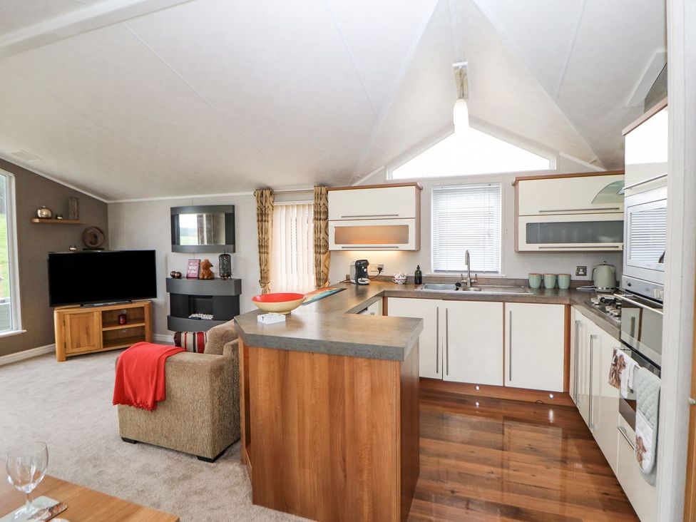 A kitchen with a couch and television at No 8 Hillcote Lodge in Cockermouth