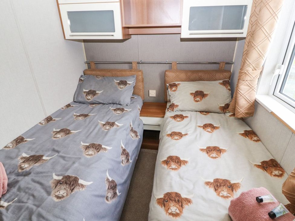 A bedroom with twin beds and a shelf at No 8 Hillcote Lodge in Cockermouth