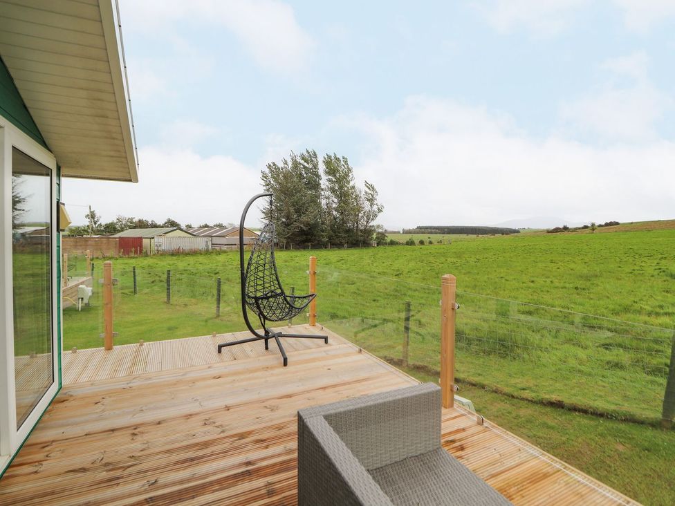 A deck with a hanging chair and outdoor furniture at No 8 Hillcote Lodge in Cockermouth