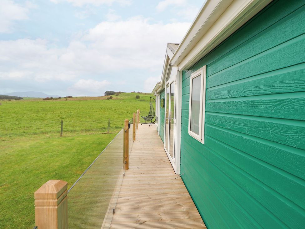 An outdoor area with a green exterior wall and decking at No 8 Hillcote Lodge in Cockermouth