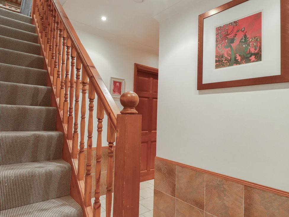 A staircase with wooden handrail leading to an upper floor at Beachcombers Apt 11