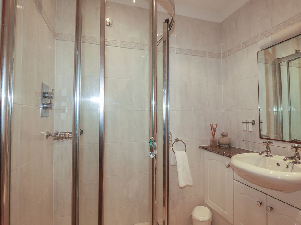 A bathroom with a shower and sink at Beachcombers Apt 11