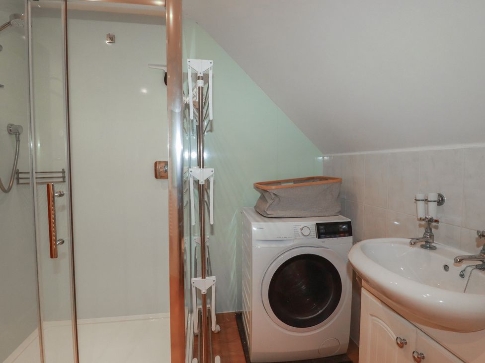 A bathroom with a shower washing machine and sink at Beachcombers Apt 11