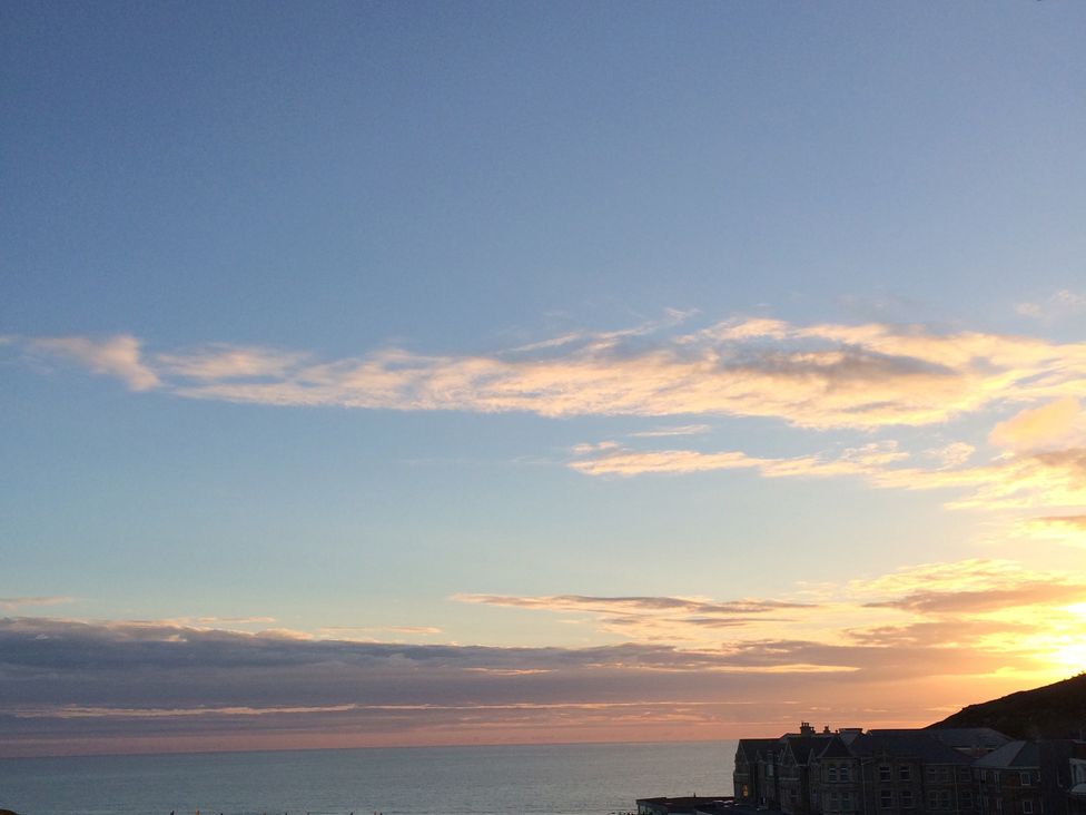 A sunset over the ocean with buildings at Beachcombers Apt 11 Watergate Bay near Newquay