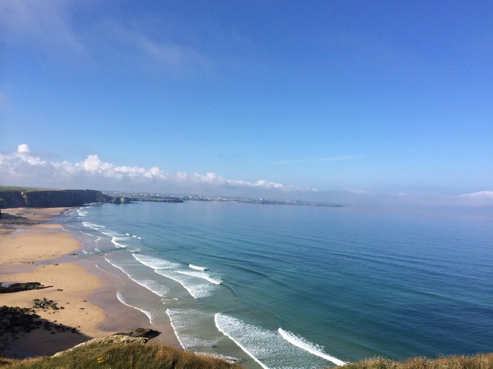 A beach with ocean waves and cliffs at Beachcombers Apt 11 Watergate Bay near Newquay