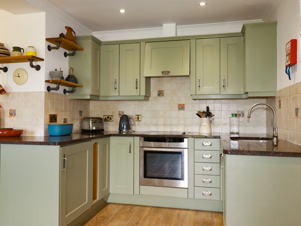 A kitchen with green cabinets and appliances at Lowenna Watergate Bay near Newquay