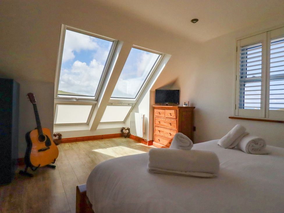 A bedroom with a bed and a guitar at Lowenna near Watergate Bay