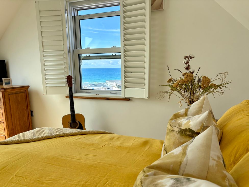 A bedroom with a bed and window overlooking the ocean at Lowenna Watergate Bay near Newquay