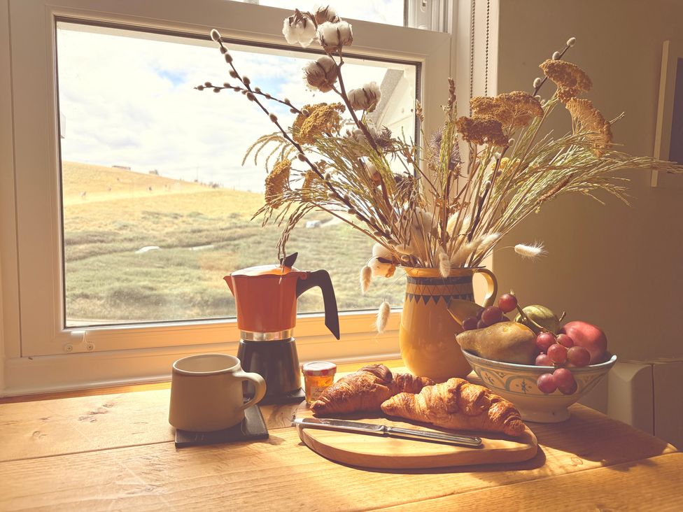 A kitchen with coffee, croissants and a fruit bowl at Lowenna, Watergate Bay near Newquay