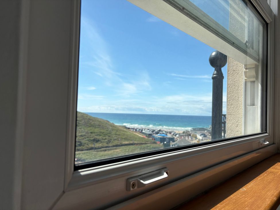 A view of the ocean and hills through a window at Lowenna Watergate Bay near Newquay