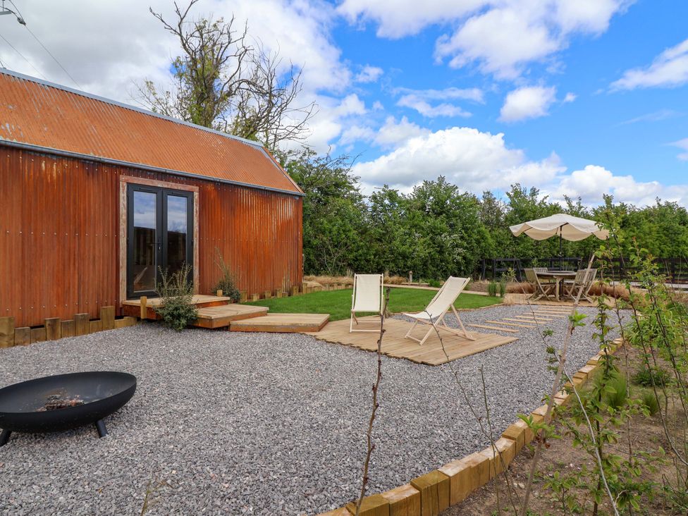 An outdoor area with a wooden deck and chairs at Shades Farm Shepherds Hut (Sleeps 4) Circenester