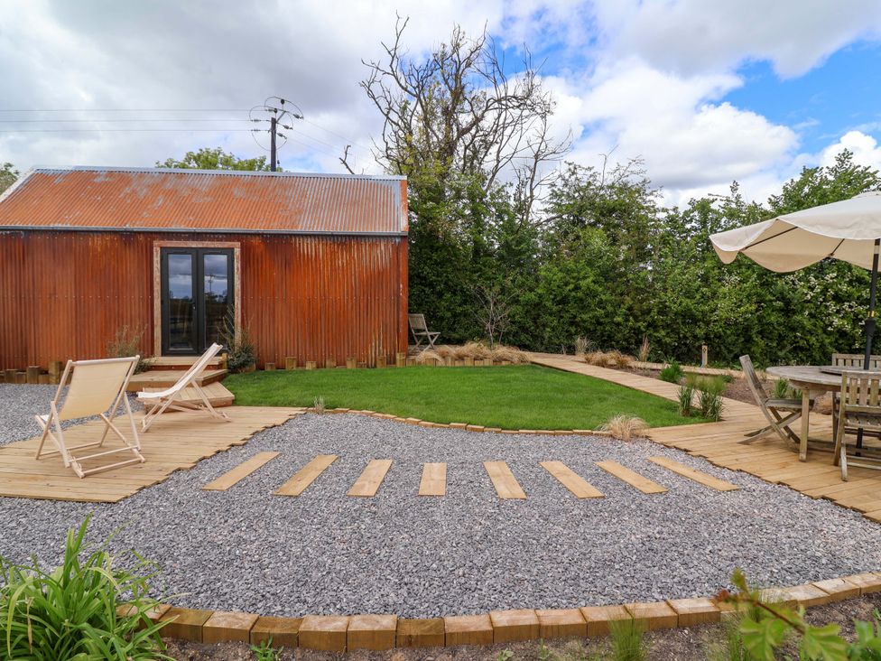 A garden with a hut, gravel, decking, and outdoor seating at Shades Farm Shepherds Hut (Sleeps 4) Cirencester