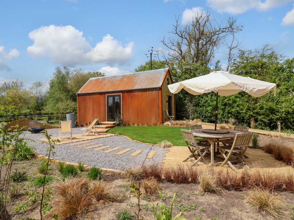 An outdoor area with a hut, table and chairs at Shades Farm Shepherds Hut (Sleeps 4) in Cirencester