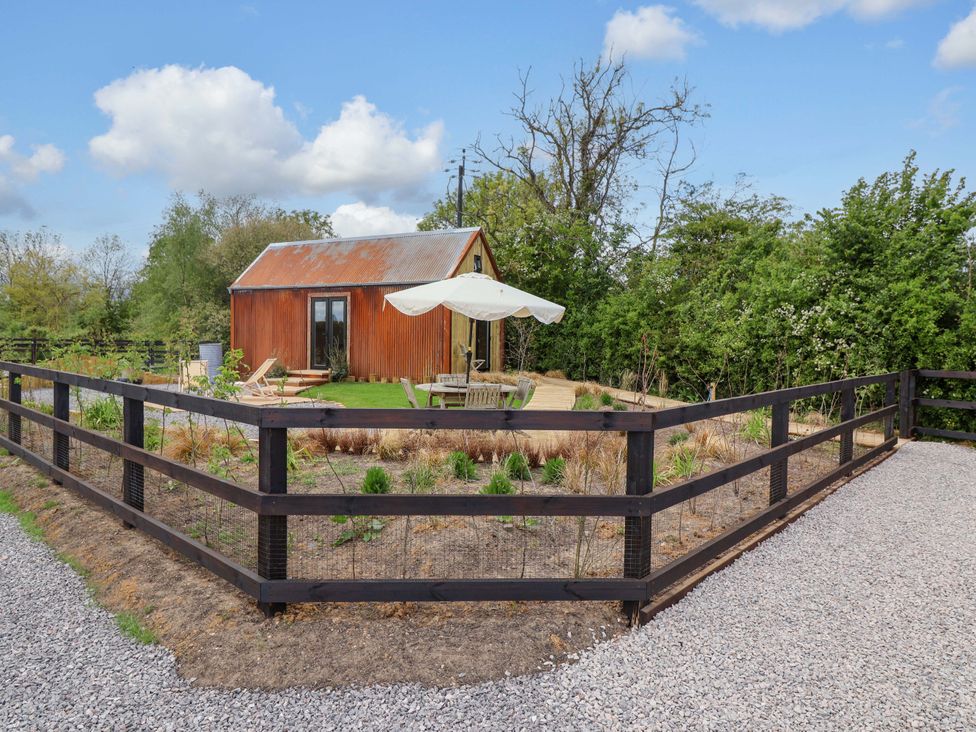A hut with outdoor seating and a fence at Shades Farm Shepherds Hut (Sleeps 4) Cirencester