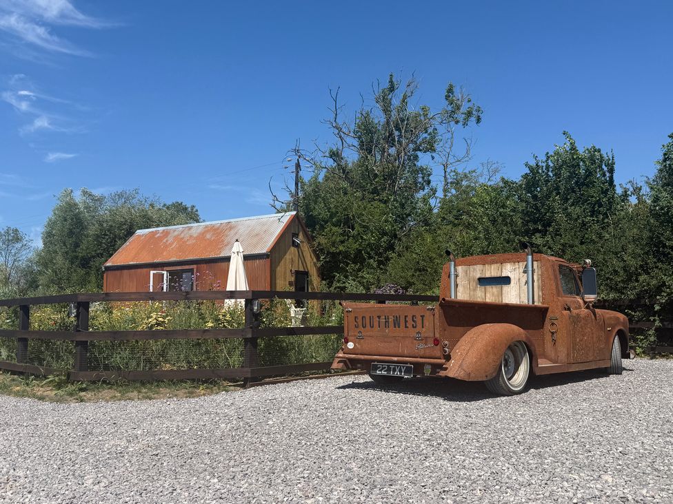 A rusty truck parked near a cabin and garden at Rustwood Manor in Minety