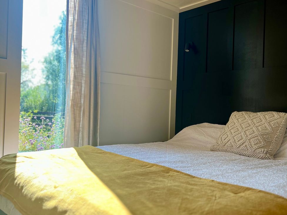 A bedroom with a bed and curtain at Rustwood Manor in Minety