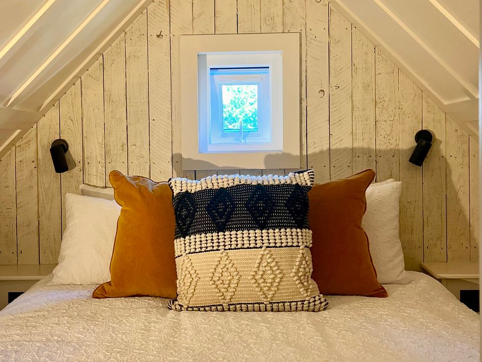 A bedroom with pillows and a window at Rustwood Manor in Minety