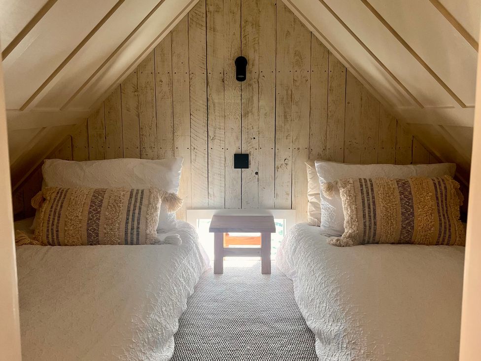 A bedroom with two beds and a small table at Rustwood Manor in Minety