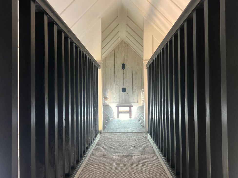 A hallway with a railing and wooden paneling at Rustwood Manor Minety