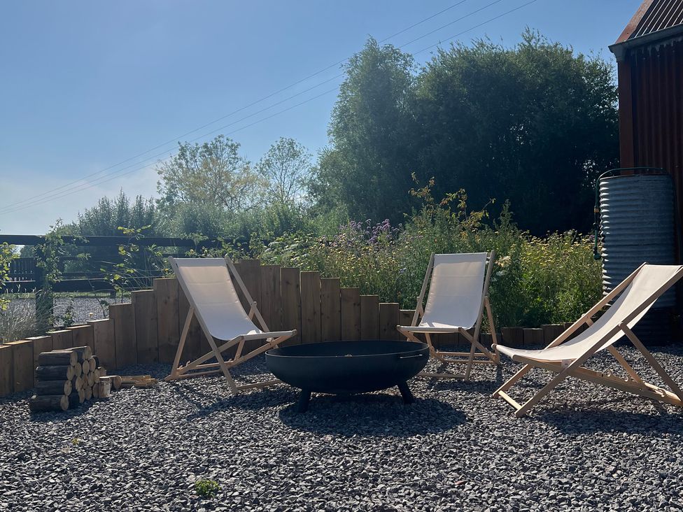 An outdoor seating area with deck chairs and a fire pit at Rustwood Manor in Minety