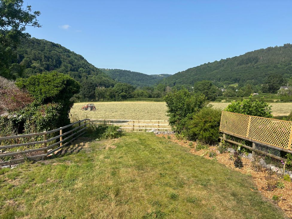 A view of a field with a tractor and mountains at Araelfa in Llwynmawr