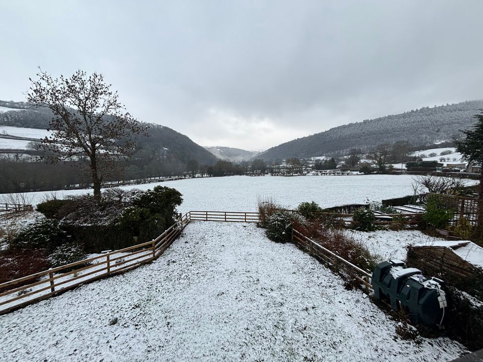 A snowy field with a tree and fence at Araelfa in Llwynmawr