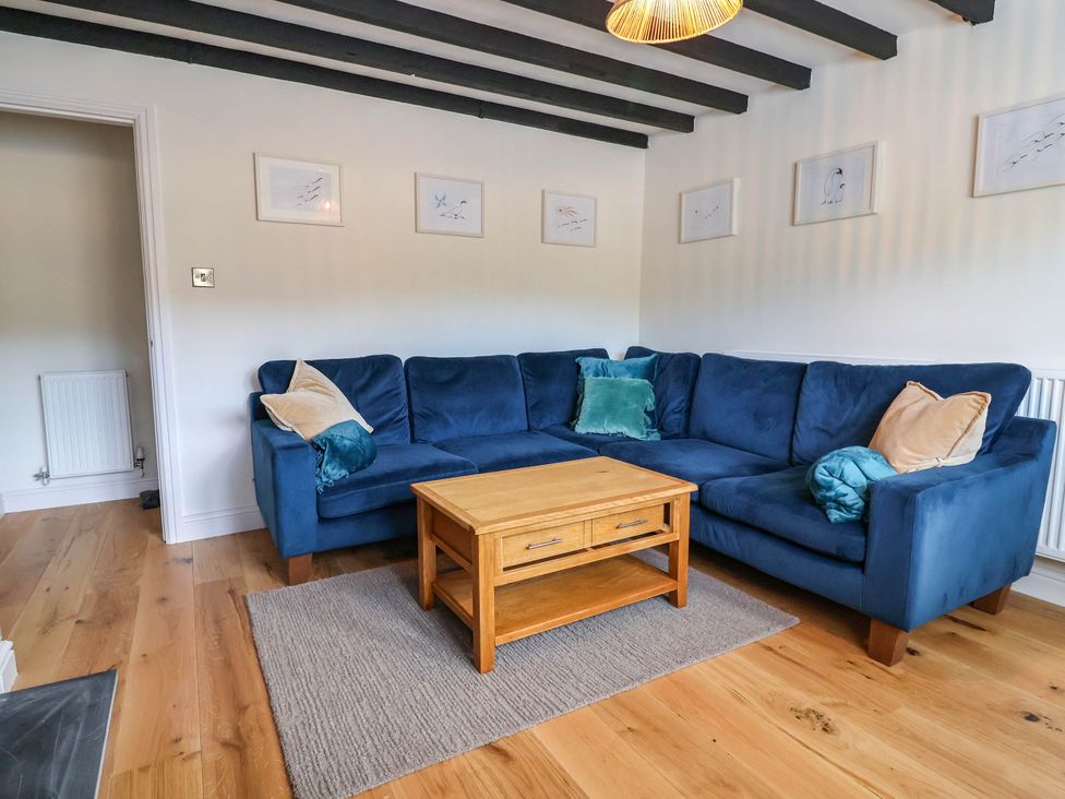 A living room with a blue sofa and wooden coffee table at Araelfa in Llangollen