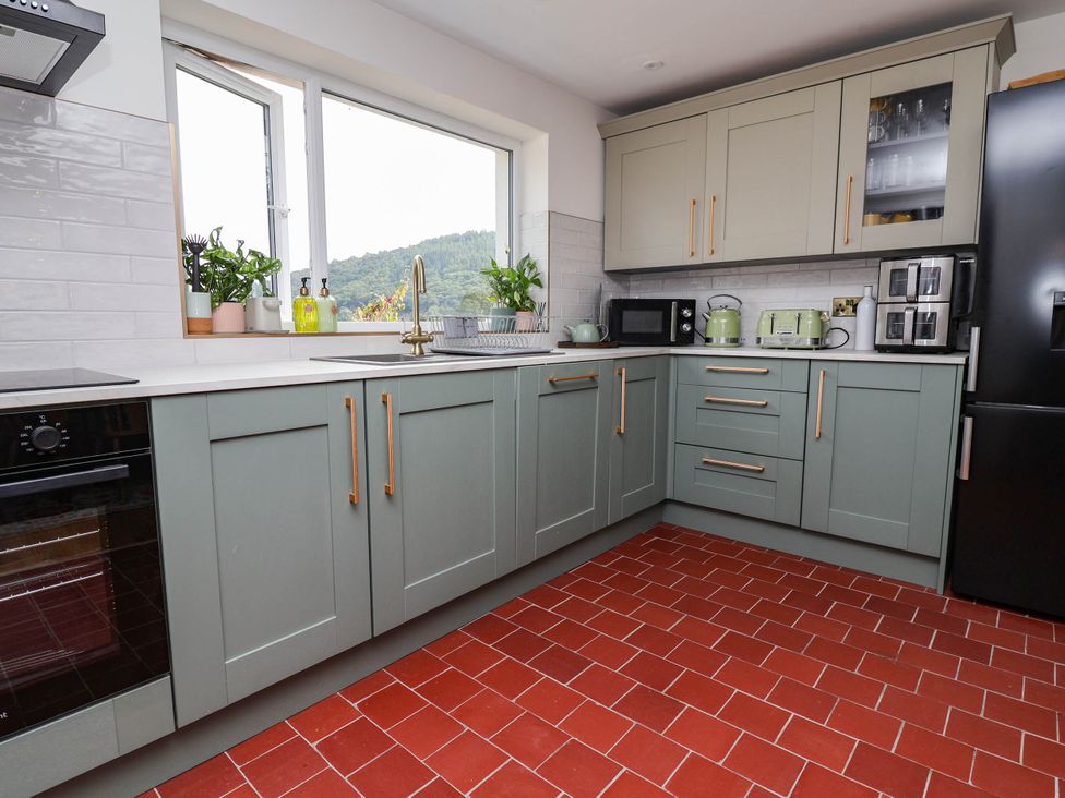 A kitchen with green cabinets and appliances at Araelfa in Llangollen