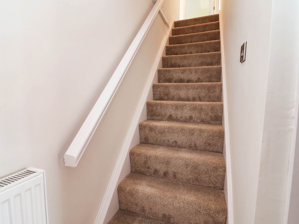 A staircase with a handrail and wall lights at Araelfa in Llangollen