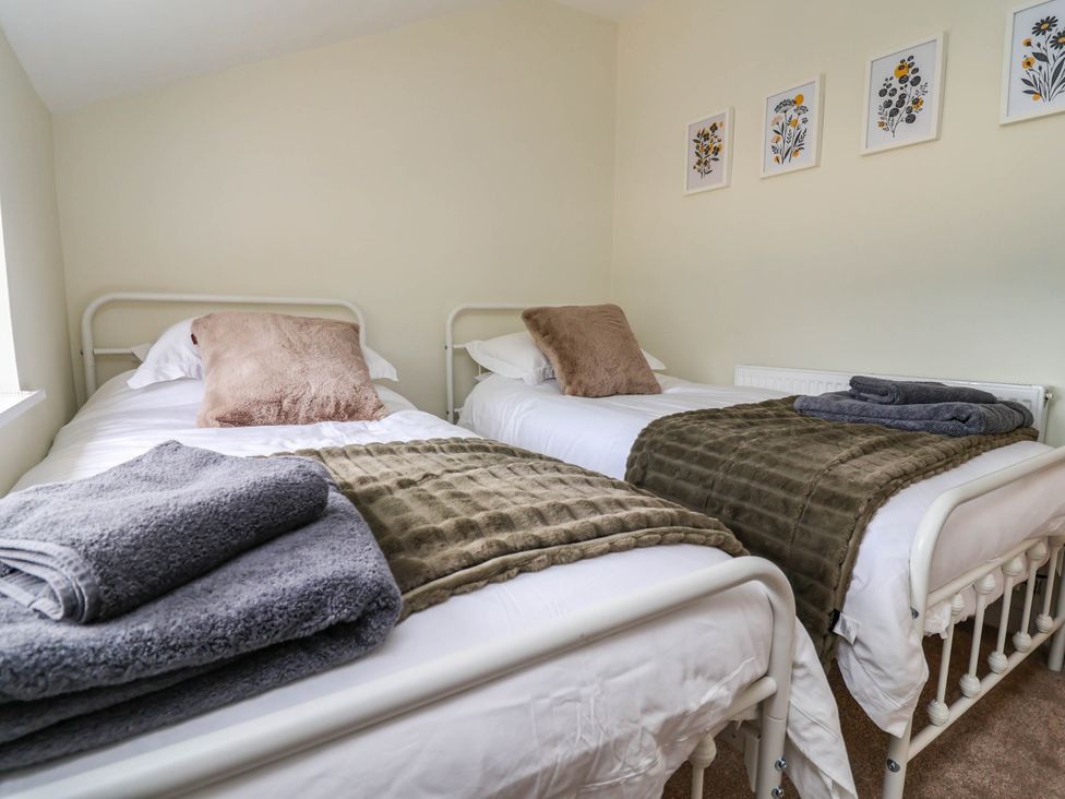 A bedroom with twin beds and decorative pictures at Araelfa in Llangollen