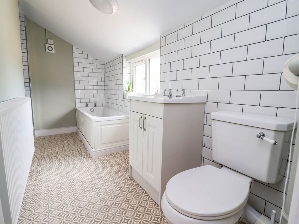 A bathroom with a bath tub, sink, and toilet at Araelfa in Llangollen