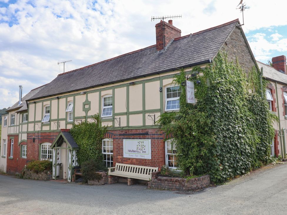 A building with signage and a bench at Mulberry Inn in Llangollen