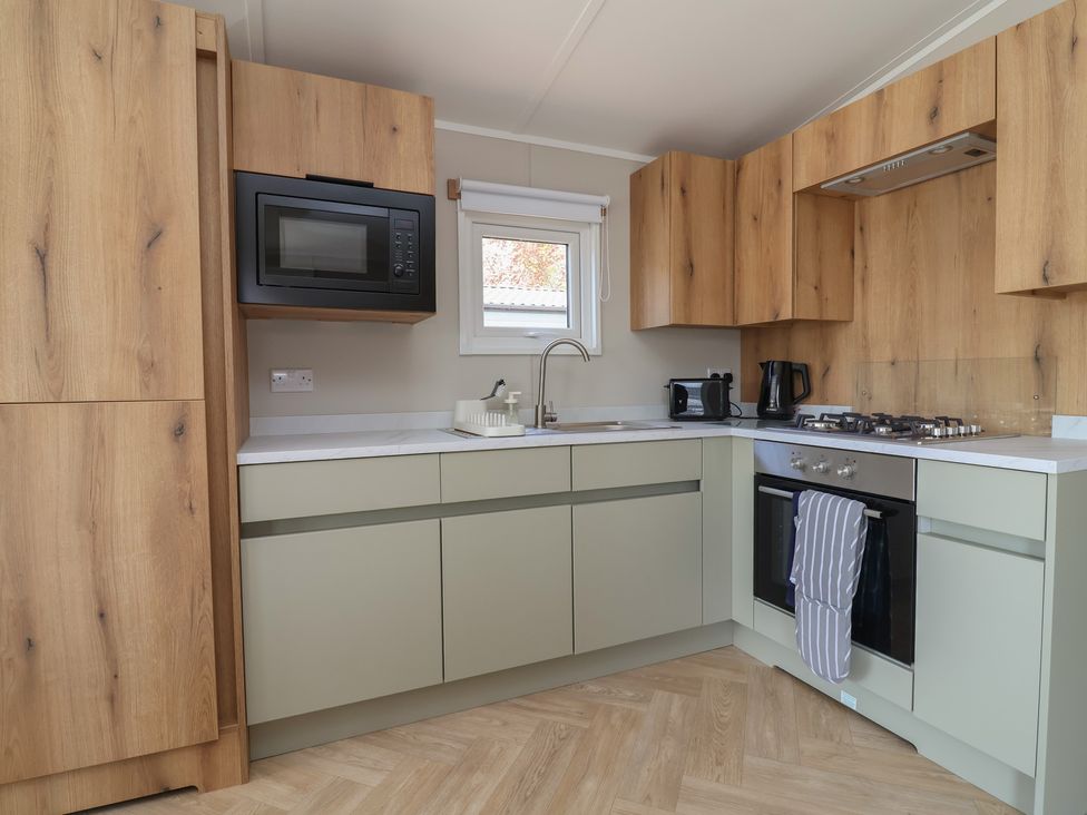 A kitchen with cabinets, microwave, stove and sink at No.20 - The Oaks in Delamere