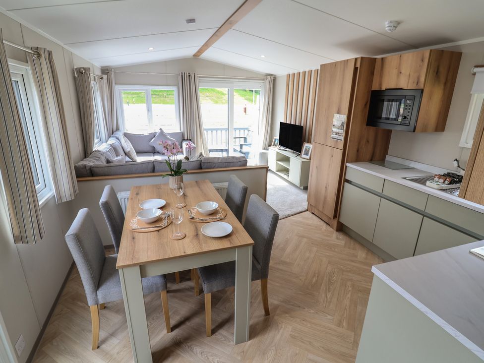 A living room and dining area with a sofa and table at The Oaks 2 Bedrooms in Delamere