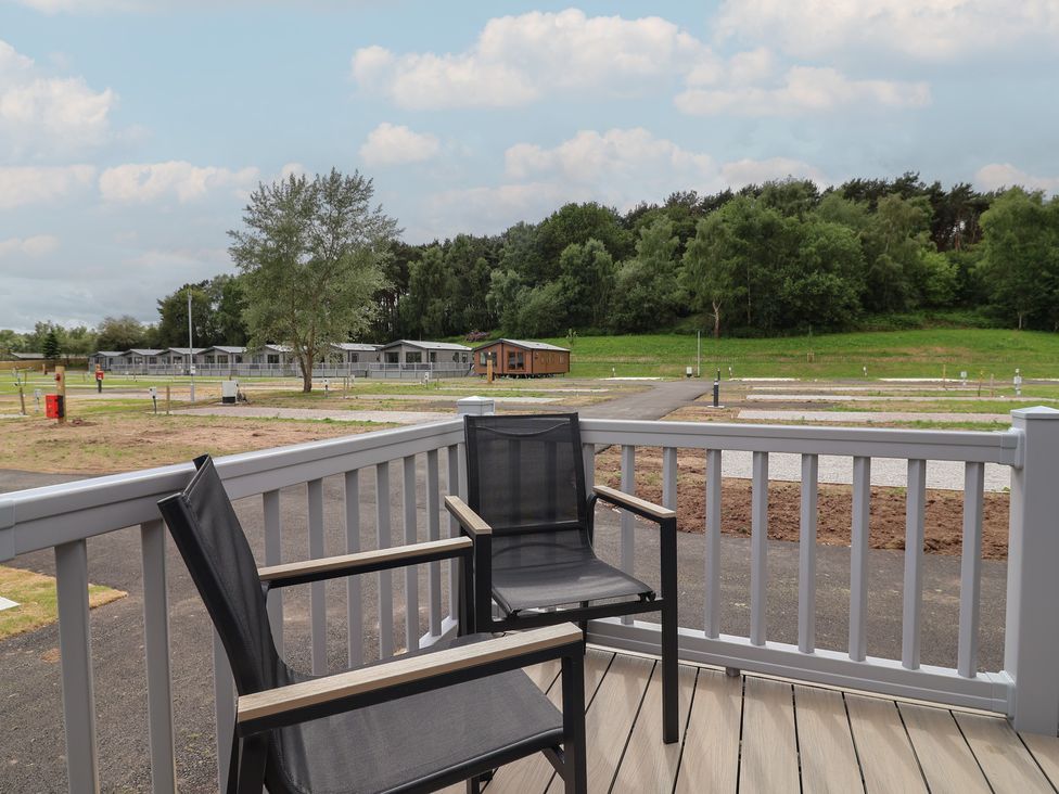 A deck with chairs overlooking vacation homes at The Oaks 2 Bedrooms in Delamere