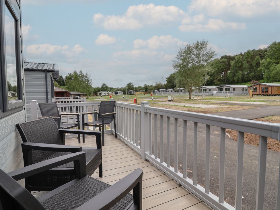 A deck with chairs overlooking a landscape at The Oaks 2 Bedrooms in Delamere