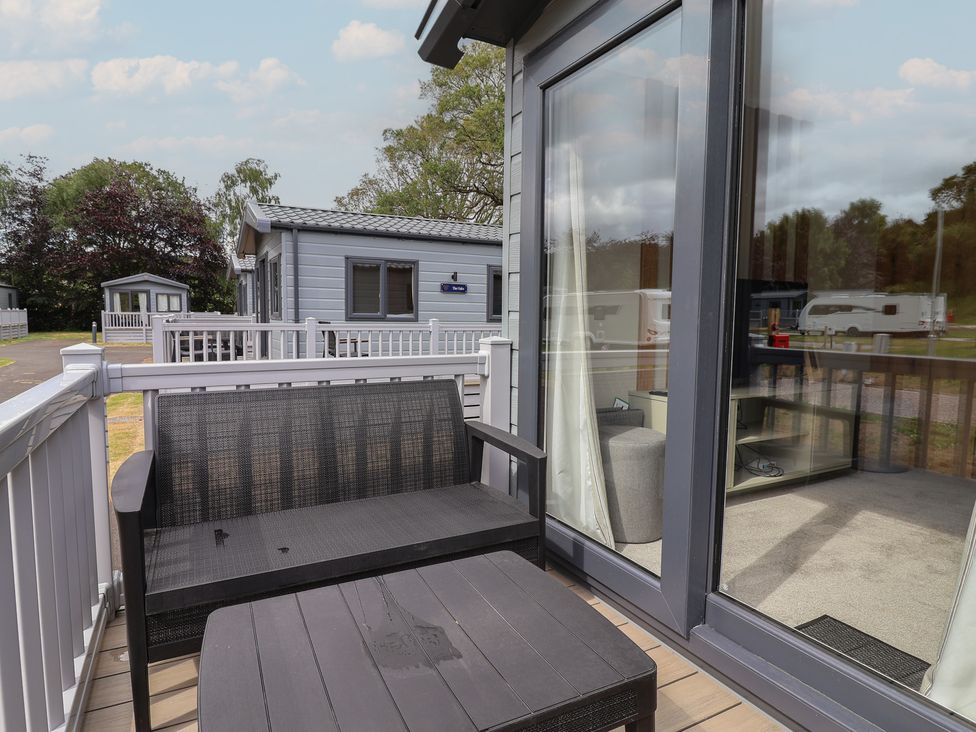 An outdoor seating area with a table and chair at The Oaks 2 Bedrooms in Delamere