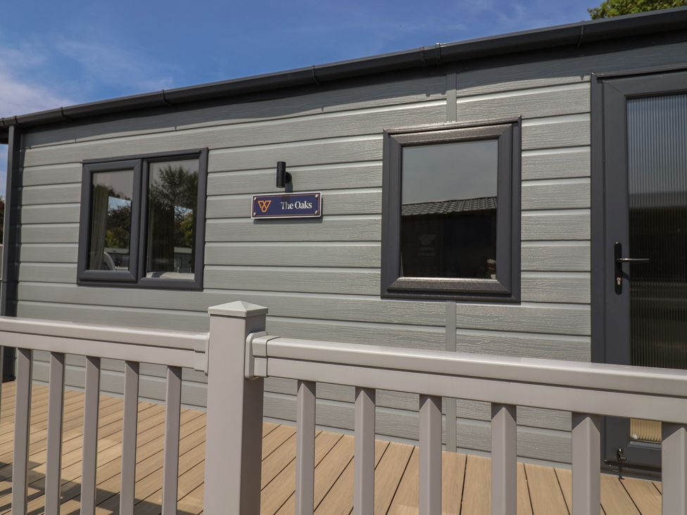 An exterior view of The Oaks cabin with windows and decking in Delamere