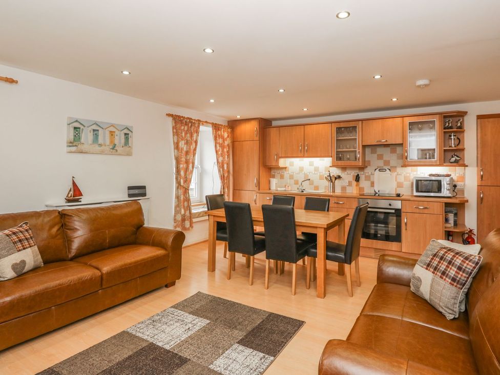 A living room with a sofa and dining area at Flour Loft in Anstruther