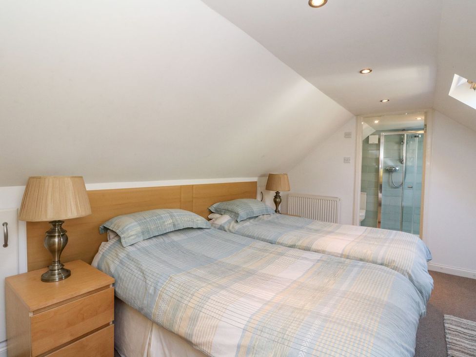 A bedroom with twin beds and a shower area at Hay Loft in Anstruther