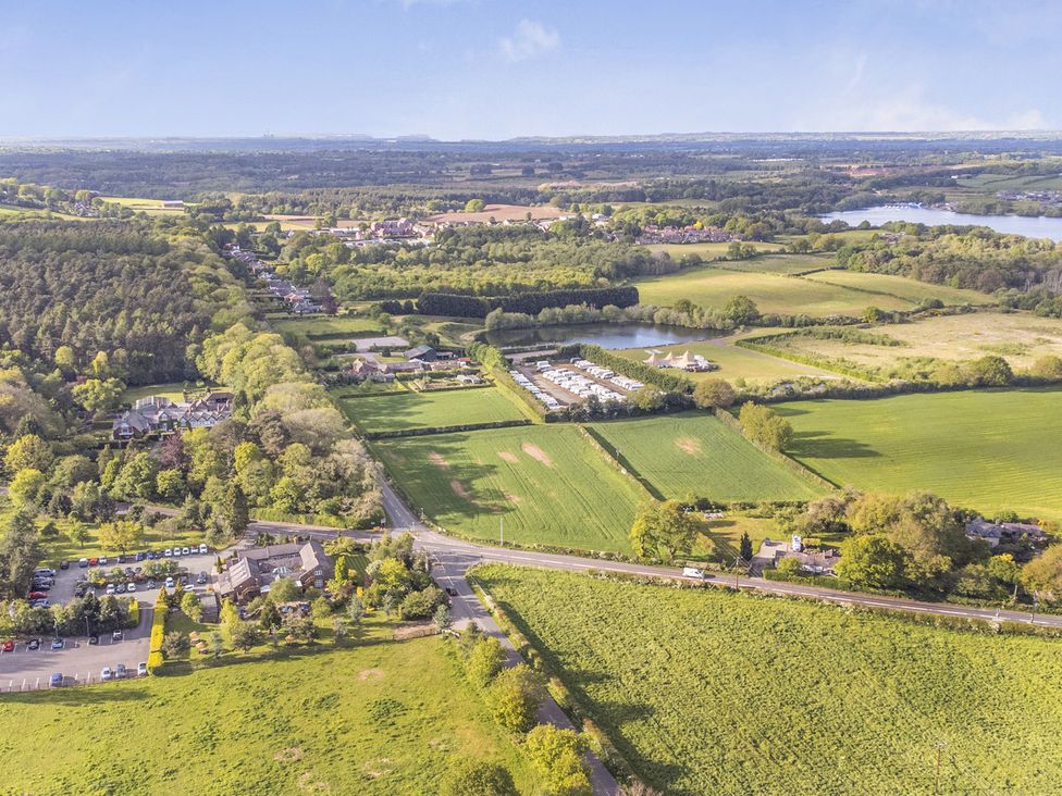 An aerial view of fields, trees, houses and a lake at Cedar Lodge 2 Bedrooms with hot tub in Delamere