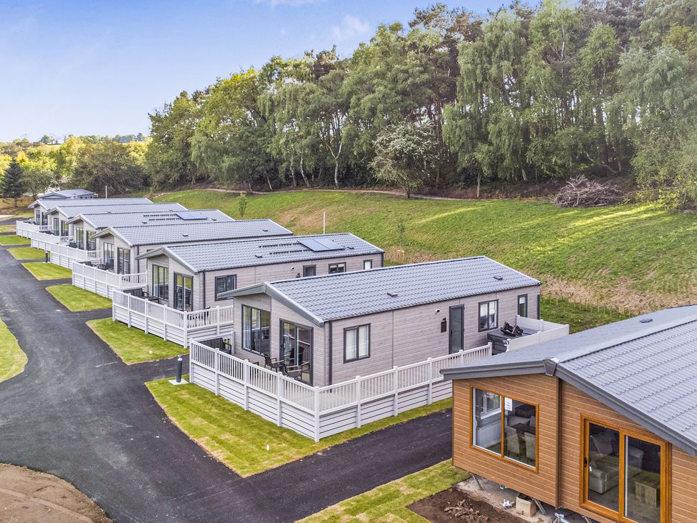 A row of lodges with a pathway and garden at Cedar Lodge 2 Bedrooms with hot tub Delamere